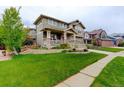 Beautifully landscaped front yard with lush green lawn, sidewalk, and inviting exterior at 14200 W 86Th Pl, Arvada, CO 80005