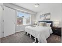 A bright bedroom features a cozy queen bed, soft gray carpet, and a window offering neighborhood views at 1064 Depew St, Lakewood, CO 80214