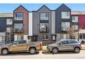 Modern townhomes with varying color schemes offer curb appeal and contemporary design elements, showcasing a vibrant street scene at 1064 Depew St, Lakewood, CO 80214