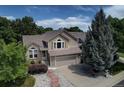 Beautifully landscaped home with a two-car garage, complemented by mature trees and a stone pathway at 8258 S Reed Way, Littleton, CO 80128