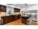 Well-lit kitchen with dark cabinets, stainless steel appliances, and breakfast bar seating at 7636 S Allison Ct, Littleton, CO 80128