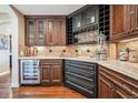 Custom bar area with wooden cabinets, wine storage, granite countertops, and a beverage fridge at 5672 S Nome St, Englewood, CO 80111