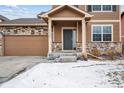 Front entrance of a two-story house with stone accents and a gray door at 11590 River Oaks Ln, Commerce City, CO 80640