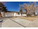 This single-story home features a white brick exterior, a front-facing garage, and a well-kept lawn at 6699 S Pennsylvania St, Centennial, CO 80121