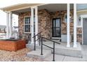 Covered front porch with stone pillars, a wooden planter, and small seating area at 1682 Dorothy Cir, Longmont, CO 80503