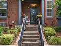 Inviting front porch with concrete stairs, black metal railing, brick facade, and flower planters at 8450 E 29Th Ave, Denver, CO 80238