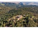Expansive aerial view showcasing a log home surrounded by dense forest and rolling hills at 2518 N State Highway 67, Sedalia, CO 80135