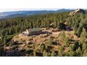Scenic exterior showcasing a hilltop home with a deck surrounded by majestic pines and scenic mountain views at 2518 N State Highway 67, Sedalia, CO 80135
