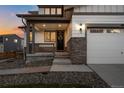Inviting front porch featuring stone accents, a dark front door with wreath, and a cozy seating area at 6696 Kenzie Cir, Castle Pines, CO 80108