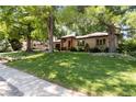 Inviting single-story home with a lush green lawn and mature trees offering shade and a welcoming atmosphere at 909 S Monroe St, Denver, CO 80209