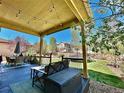 Inviting covered back patio with string lights and outdoor seating, perfect for relaxing and entertaining with a view of the yard at 10995 Quintero St, Commerce City, CO 80022