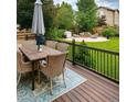 Inviting backyard deck with a dining table and view of a fire pit and well-maintained green lawn at 10995 Quintero St, Commerce City, CO 80022