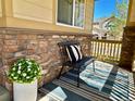 Inviting front porch featuring stone accents, a comfortable chair and stylish striped rug, creating a welcoming entrance at 10995 Quintero St, Commerce City, CO 80022