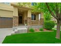 Inviting front porch with stone pillars and decorative railing, complemented by lush landscaping and manicured lawn at 10995 Quintero St, Commerce City, CO 80022