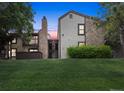 An inviting exterior showcasing a stone accent chimney, well-maintained lawn, and a tranquil setting at dusk at 7740 W 87Th Dr # A, Arvada, CO 80005