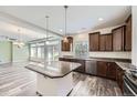 Open kitchen features a central island, granite countertops, and wood cabinets for a modern design at 133 Poppy View Ln, Erie, CO 80516
