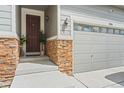 Inviting front entry with dark wood door, stone accents, and stylish outdoor lighting at 7410 S Old Hammer Way, Aurora, CO 80016