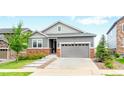 Charming home featuring gray siding, stone accents, well-maintained lawn, and an attached garage at 7410 S Old Hammer Way, Aurora, CO 80016