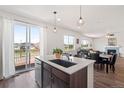 Bright, open-concept kitchen featuring an island with breakfast bar, modern appliances, and sliding glass doors to the deck at 7410 S Old Hammer Way, Aurora, CO 80016