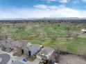 Aerial view of neighborhood homes backing onto a golf course with mountain views in the distance at 787 Kendall Ct, Lakewood, CO 80214