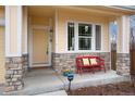 Charming front porch with stone accents, a bright yellow door, and a red bench with cheerful cushions at 787 Kendall Ct, Lakewood, CO 80214