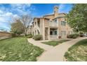 Inviting condo exterior with well-maintained landscaping, walkways, and a cheerful teal accent color at 8475 Pebble Creek Way # 204, Highlands Ranch, CO 80126
