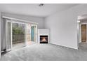 Bright living room featuring a cozy fireplace, plush carpeting, and access to a private deck at 8475 Pebble Creek Way # 204, Highlands Ranch, CO 80126