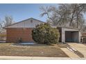 Charming single-story brick home featuring a carport and mature landscaping under a clear, blue sky at 6032 Estes St, Arvada, CO 80004