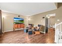 Neutral living room featuring hardwood floors, rocking chairs, a mounted TV, and adjacent dining area at 2911 S Olathe Way, Aurora, CO 80013