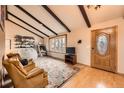 Living room with vaulted ceilings, exposed beams, two chairs, and a bay window at 16463 E Girard Ave, Aurora, CO 80013