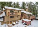 Charming two-story home with wooden deck, hot tub, surrounded by snowy landscape at 45 Oak Way, Evergreen, CO 80439