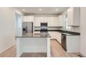 Bright kitchen showcasing white cabinets, stainless steel appliances, and a large island with quartz countertops at 7367 S Yank Ct, Littleton, CO 80127