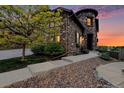 Stone-accented home featuring a turret-style architectural design, complemented by meticulous landscaping at 10705 Pinewalk Way, Highlands Ranch, CO 80130