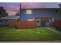 Charming townhome featuring a well-maintained lawn, stone accents, and a private wooden fence at dusk at 1211 W 112Th Ave # B, Denver, CO 80234