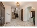 Bright foyer with tile flooring, chandelier lighting, staircase to the second floor, and arched doorway at 5361 Nassau Cir, Cherry Hills Village, CO 80113