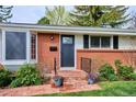 Close-up of the home's entrance, showing a brick facade, quaint porch, and vibrant flower pots at 6587 S Clarkson St, Centennial, CO 80121