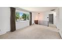 Bright living room featuring a large window with views, neutral carpet and a wrought iron railing at 3065 Zion St, Aurora, CO 80011