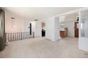 Open living room with neutral carpet, black wrought iron railing and white walls at 3065 Zion St, Aurora, CO 80011
