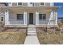 Inviting front porch with white railing and columns, leading to a gray front door with house number at 18049 E 106Th Ave, Commerce City, CO 80022