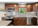 Modern kitchen with stainless steel appliances, custom cabinets, and a bright window overlooking greenery at 375 Castlewood Dr, Evergreen, CO 80439