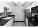 Well-lit kitchen featuring modern appliances, sleek black countertops and backsplash and light wooden flooring at 1960 S Xanadu Way # 208, Aurora, CO 80014