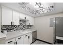 Charming kitchen with stainless steel appliances, white cabinets, mosaic backsplash, and modern track lighting at 1960 S Xanadu Way # 208, Aurora, CO 80014