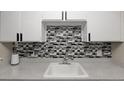 Close-up of the kitchen sink area showcasing the mosaic backsplash and countertop space at 1960 S Xanadu Way # 208, Aurora, CO 80014