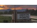 A picturesque view of the Heron Pointe community sign, set against a stunning sunset and mountain backdrop at 3572 Lissa Dr, Berthoud, CO 80513