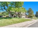Traditional two-story home boasts a well-kept lawn, mature trees, and an attached garage, enhancing its curb appeal at 5543 S Kenton Ct, Englewood, CO 80111