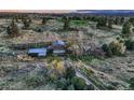 An aerial view showcases the aged farm home and landscape with a long dirt driveway and trees at 10426 Tomahawk Rd, Parker, CO 80138