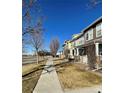 A row of charming townhomes line a sidewalk under a clear blue sky at 15612 E 96Th Way # 13E, Commerce City, CO 80022