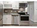 Updated kitchen features stainless steel appliances, tile backsplash, and granite countertops at 5875 E Iliff Ave # 108, Denver, CO 80222