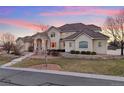 Charming stucco home showcasing a meticulously manicured lawn and stone retaining wall at 16394 W 77Th Ln, Arvada, CO 80007