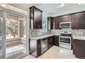 Modern kitchen featuring stainless steel appliances, granite countertops, and dark wood cabinets at 6506 Silver Mesa Dr # F, Highlands Ranch, CO 80130